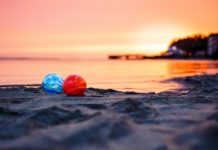 Glass Floats on the beach at sunset. There's a red float and a blue float.
