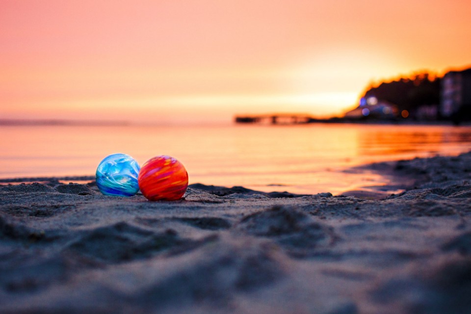 Glass Floats on the beach at sunset.  There's a red float and a blue float.