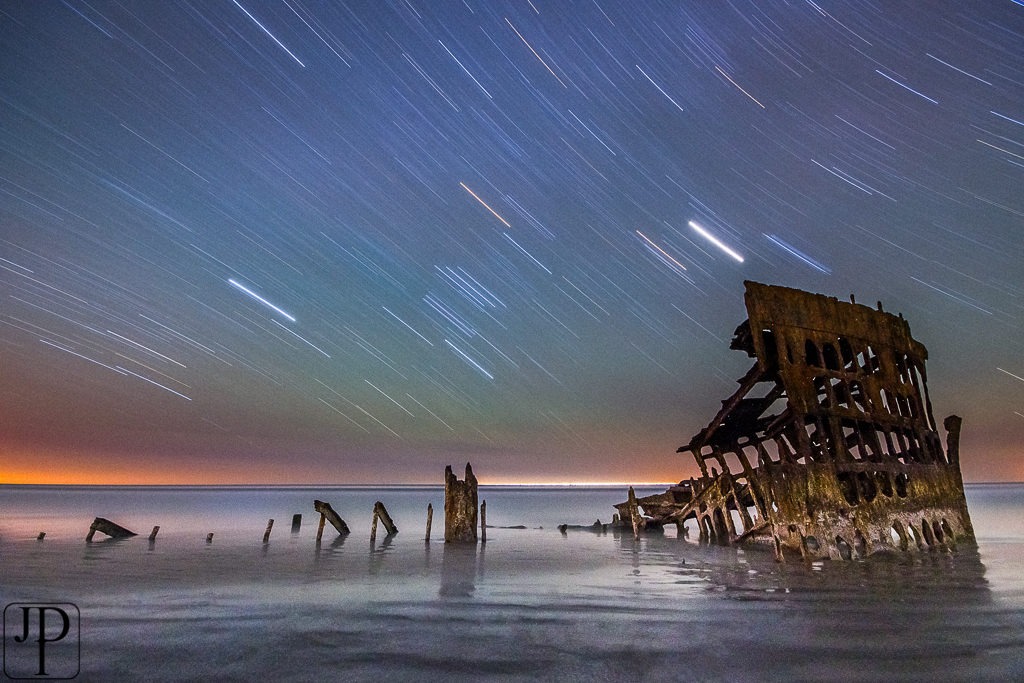 The wreck of the Peter Iredale at Fort Stevens State Park at night with stars overhead.