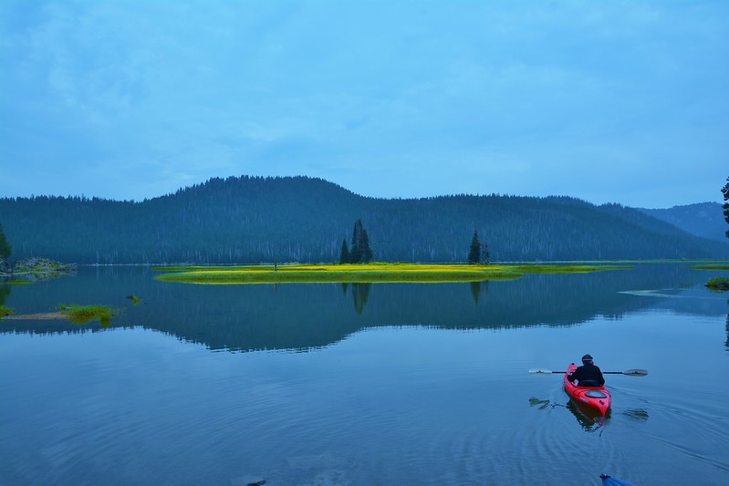 A man in a red kayak on the still waters of Sparks Lake.