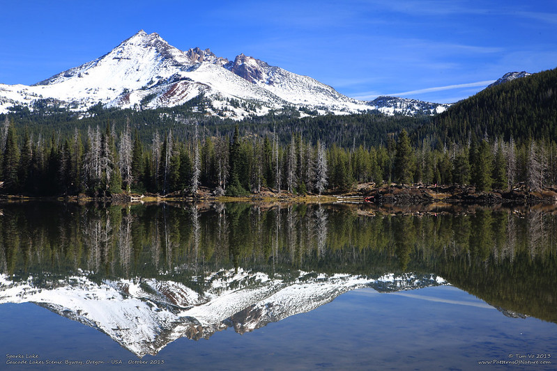 A snowcapped mountain towering above Sparks Lake and reflected in the still waters on a sunny day.