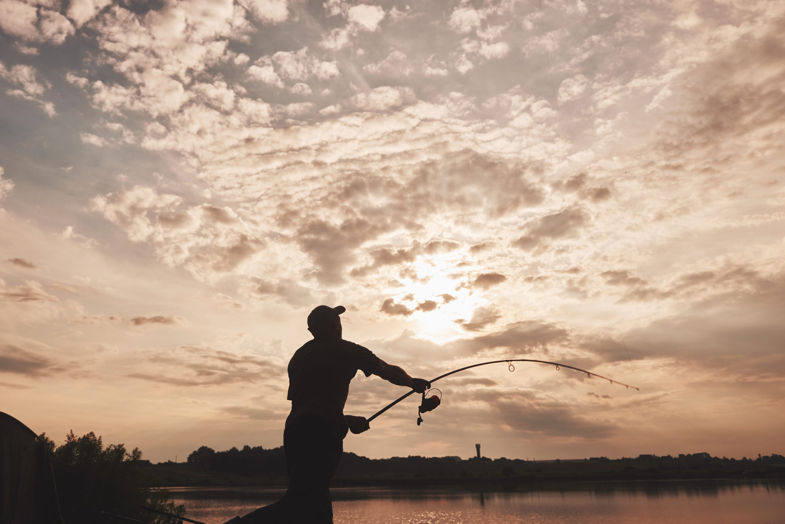 A man fishing in a lake at sunset