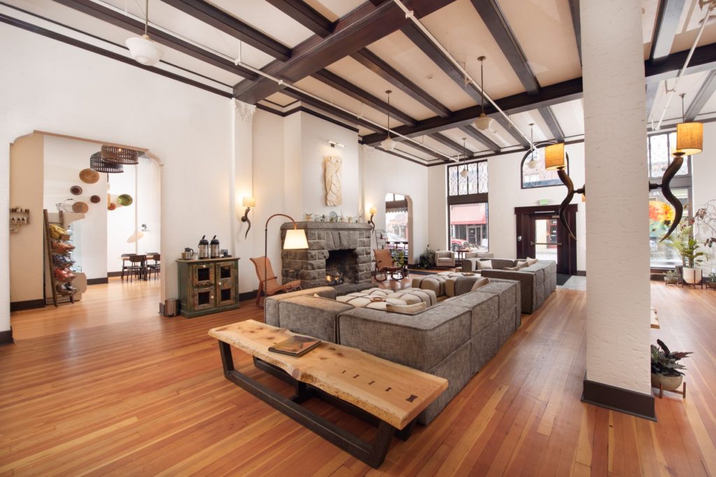 Interior of SCP Redmond hotel, with wood floors and beams and white walls and a fireplace