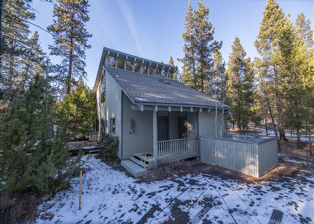 The outside of a cute little cabin surrounded by snow