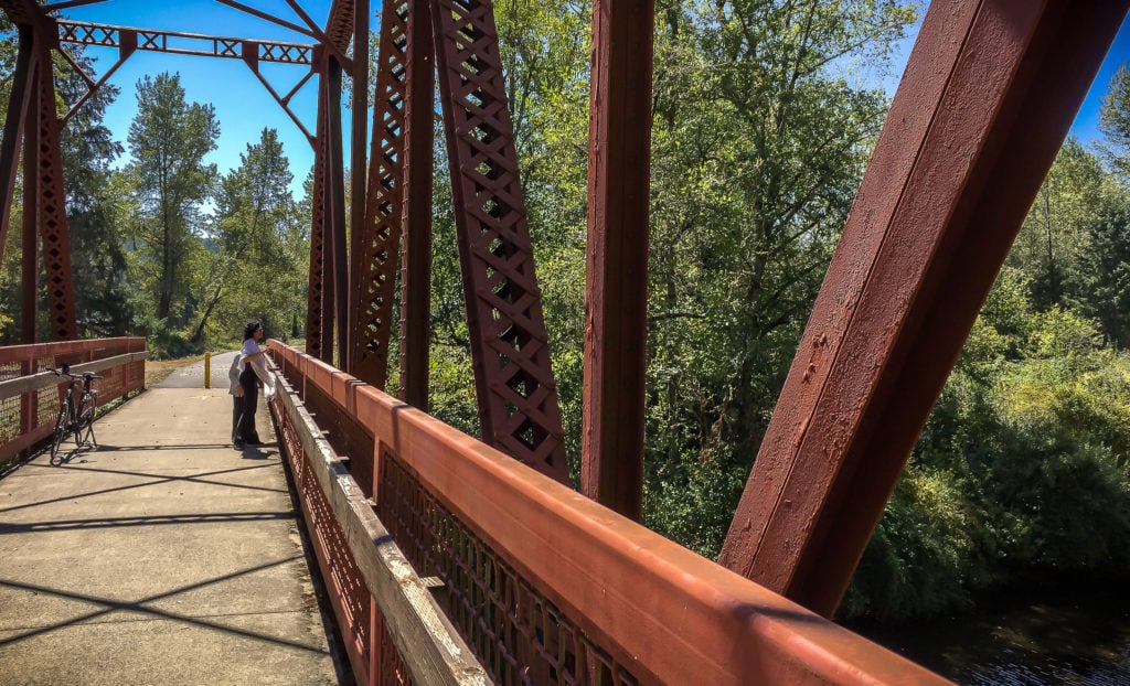 A visitor and bicycles on a steel bridge along the Row River Trail in Oregon