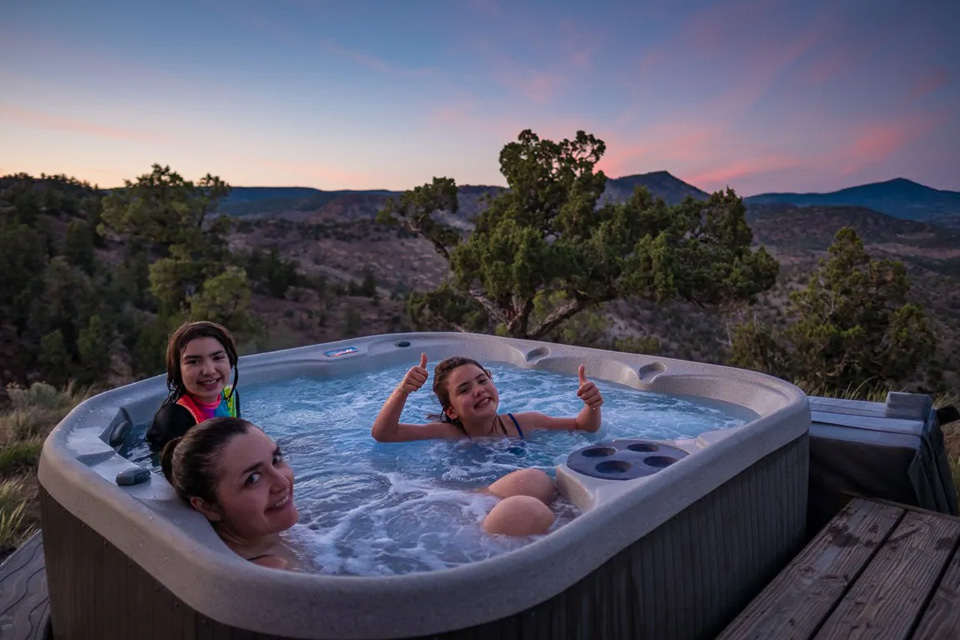 People in a hot tub at sunset with a high desert view