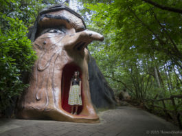 A large witches head with a woman standing in the mouth.