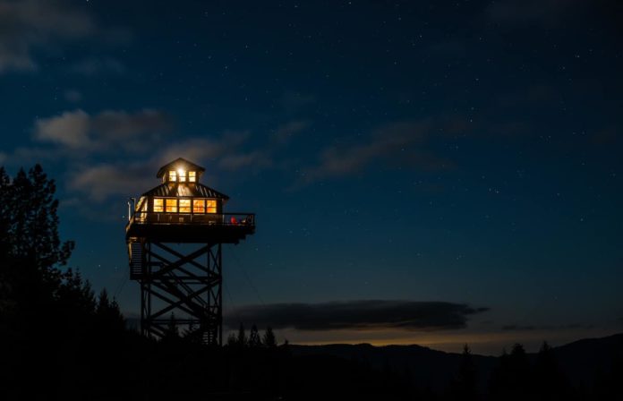 The lookout tower lit up at night under the stars