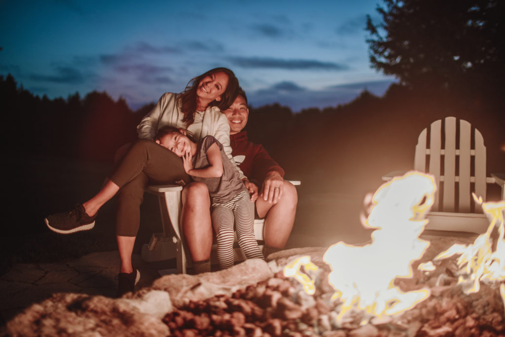 Salishan Oregon Resort - A family sitting around an outdoor fire pit at night looking happy.