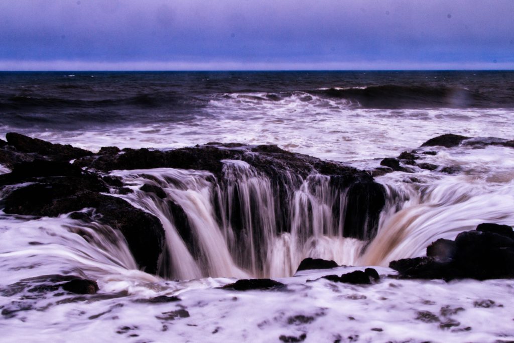 A photo of Thor's Well at low tide, with water flowing in through its open top
