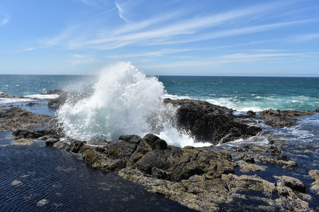 A photo of Thor's Well at high tide, with water spouting out from the top