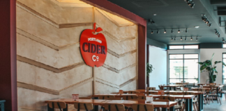 Portland Cider Co taproom tables with apple logo on the wall