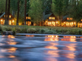 Cabins in the evening on the Metolius River. There's warm light spilling out of the cabins.