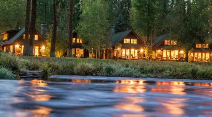 Cabins in the evening on the Metolius River. There's warm light spilling out of the cabins.