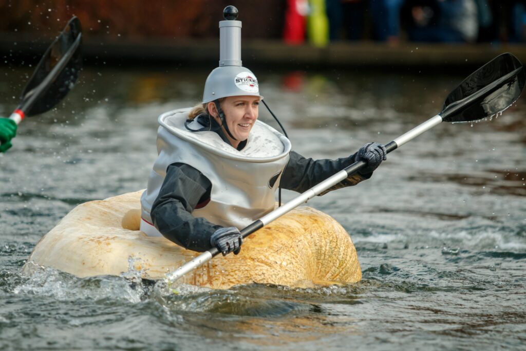 Someone in costume paddling a huge pumpkin in the West Coast Giant Pumpkin Regatta in Oregon