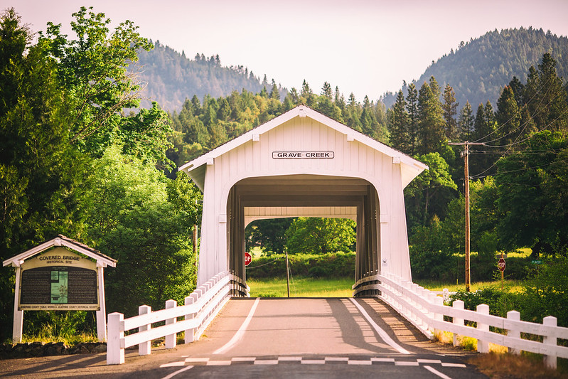 The road going through Grave Creek Covered Bridge in Oregon on a sunny day.