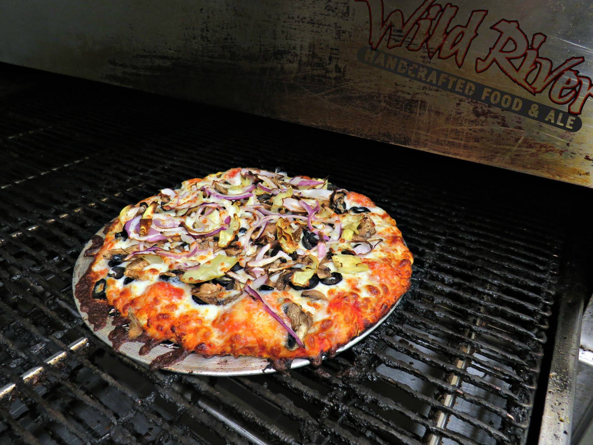 A pizza coming out of the pizza oven at Wild River Pizza