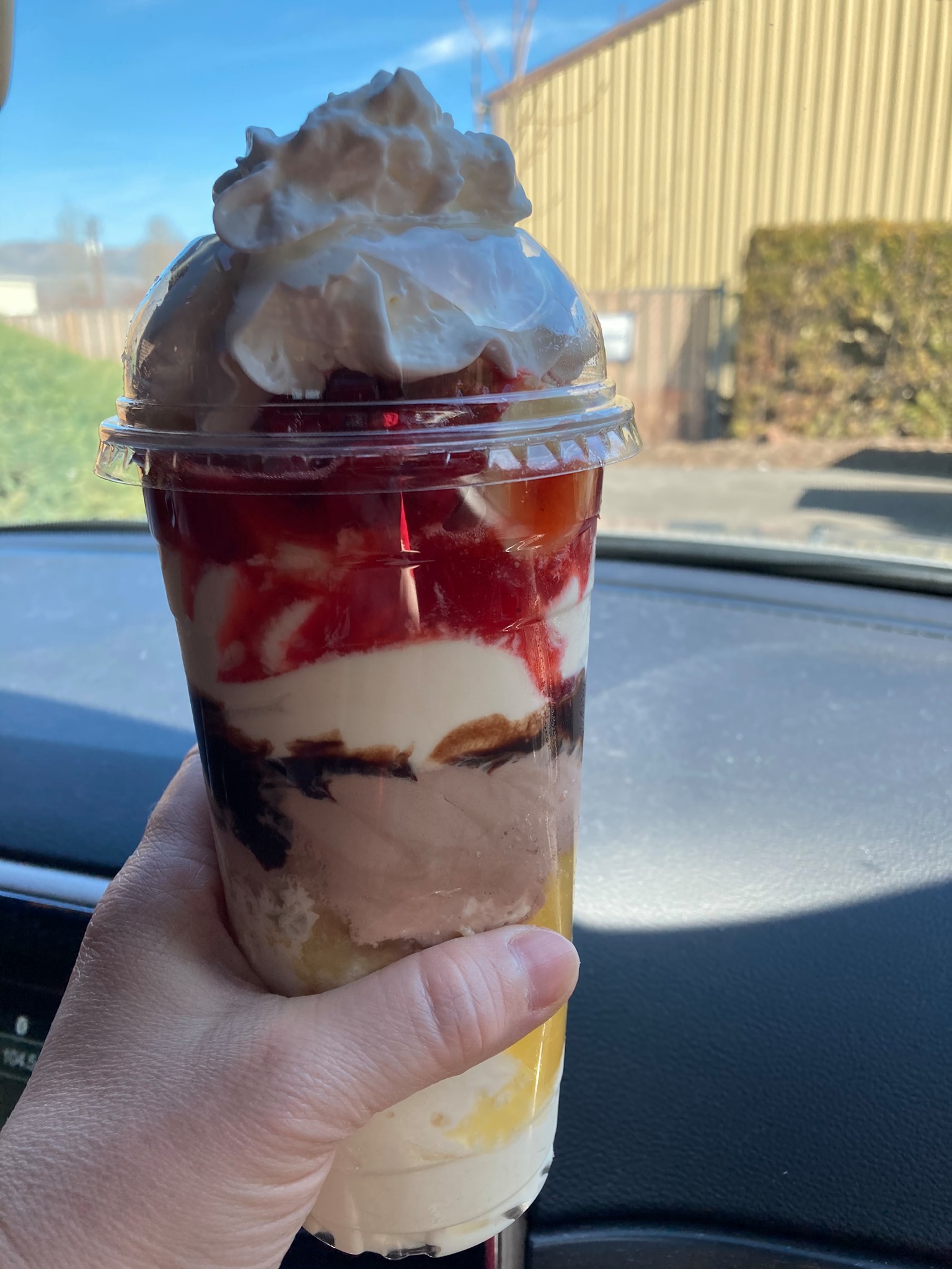 A tall colorful milkshake with whip cream from Big Jim's Drive In.