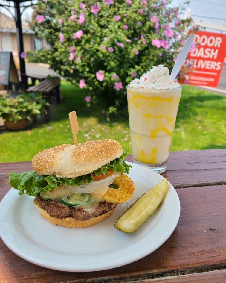 A burger with pineapple and a milkshake topped with whip cream at Jasper's Cafe in Medford Oregon.