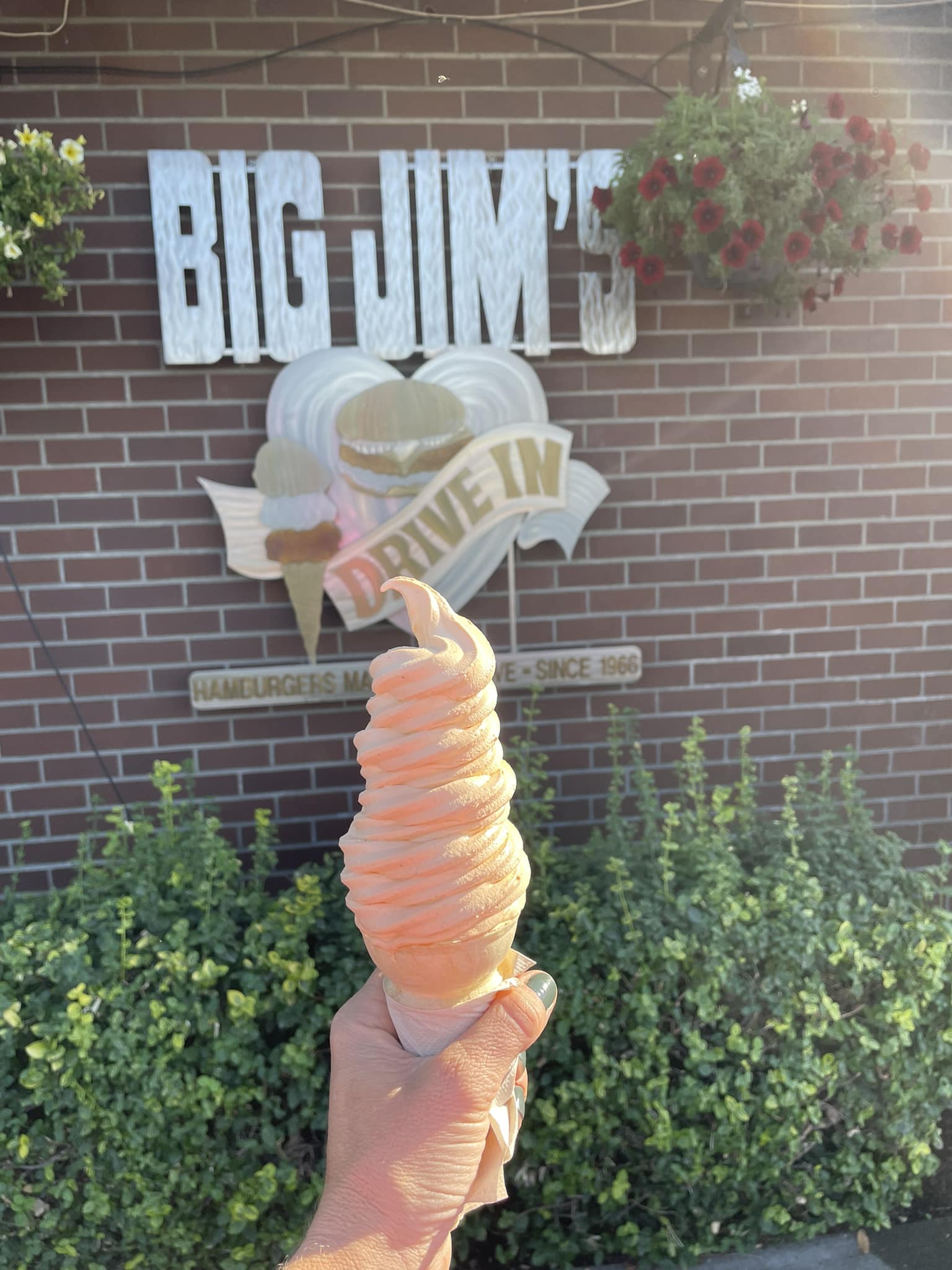 A super tall orange ice cream swirled on top of a cone at Big Jim's