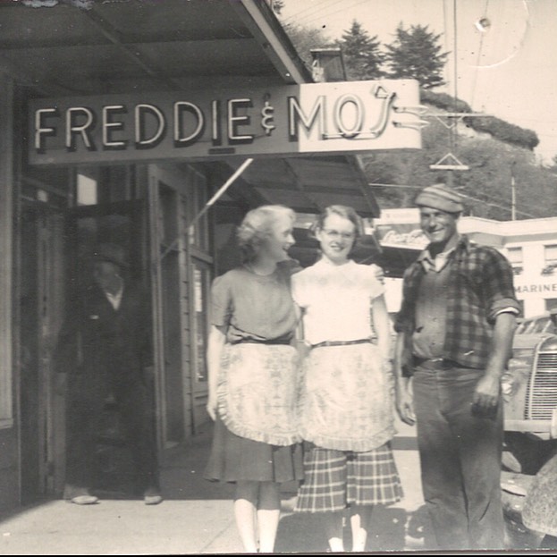 A black and white photo of Mo and a man and woman outside of the original Freddy and Mo's restaurant in Newport, Oregon.