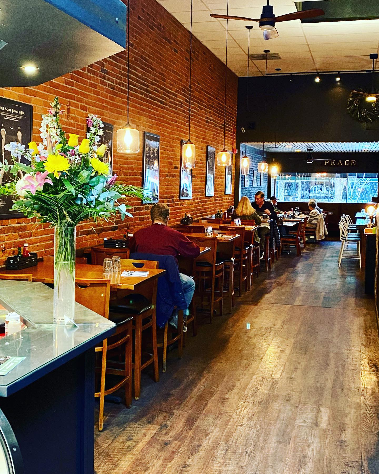 The interior of Brix Grill And Chill. Red brick walls, dark wood floors, and cool hanging lights. It looks hip and modern.