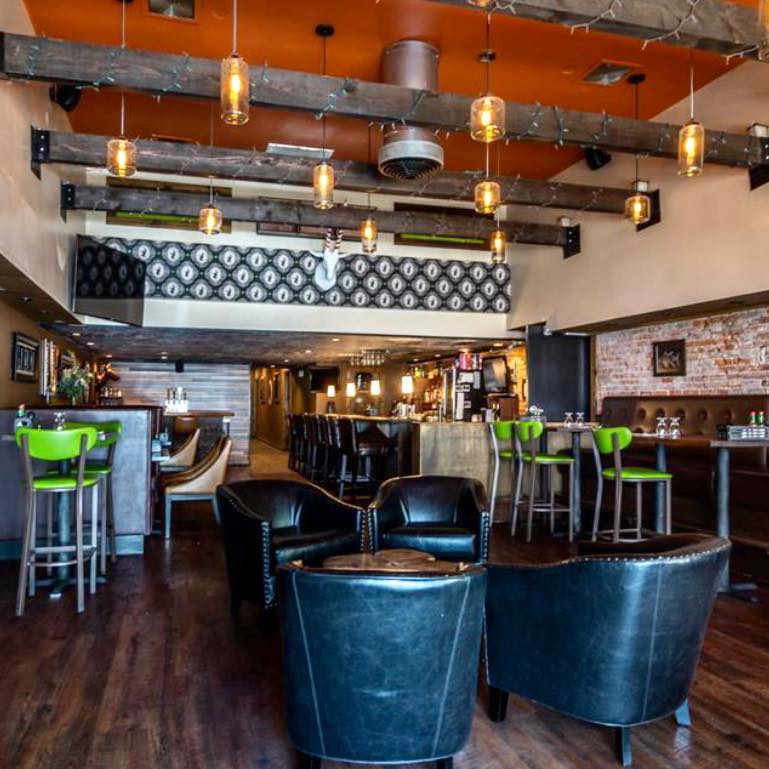 The interior of Brix Grill And Chill. Dark wood floors, cool chairs, wood beams on the ceiling and cool hanging lights. It looks hip and modern.