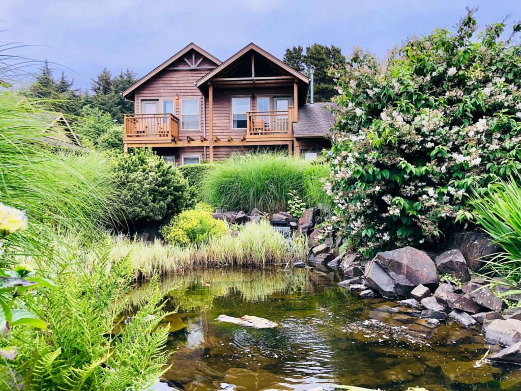 The outside of Inn At Cannon Beach with a small pond and pretty flowers.