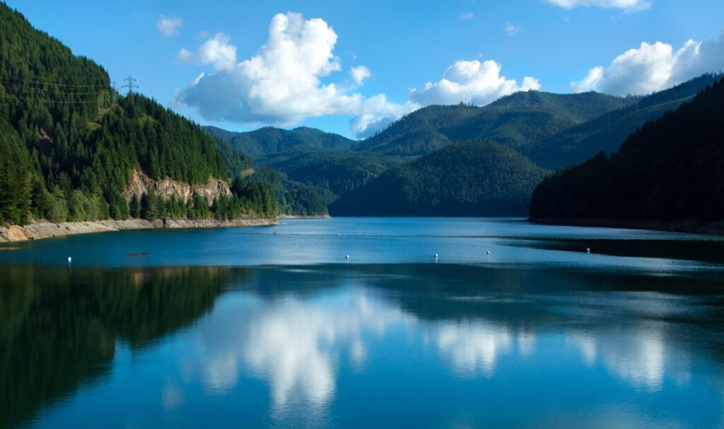 Clouds reflected in Detroit Lake between forested hills