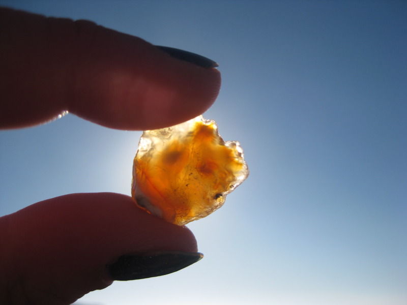 fingers in a silhouette holding a beach agate up to the sun