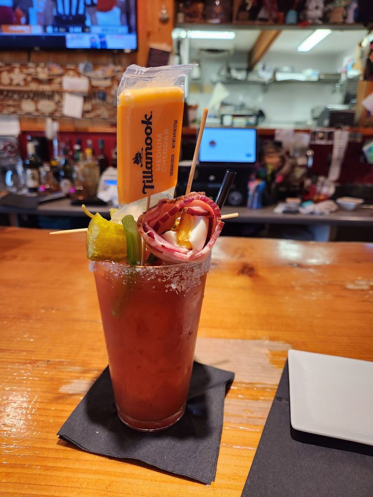 A bloody Mary with bacon, Tillamook cheese, and other things sticking out the top of the drink on skewers.