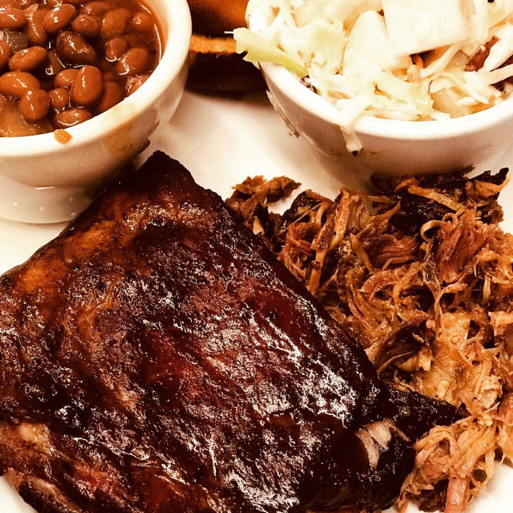 Delicious looking smoked BBQ meat with baked beans and slaw on the side.