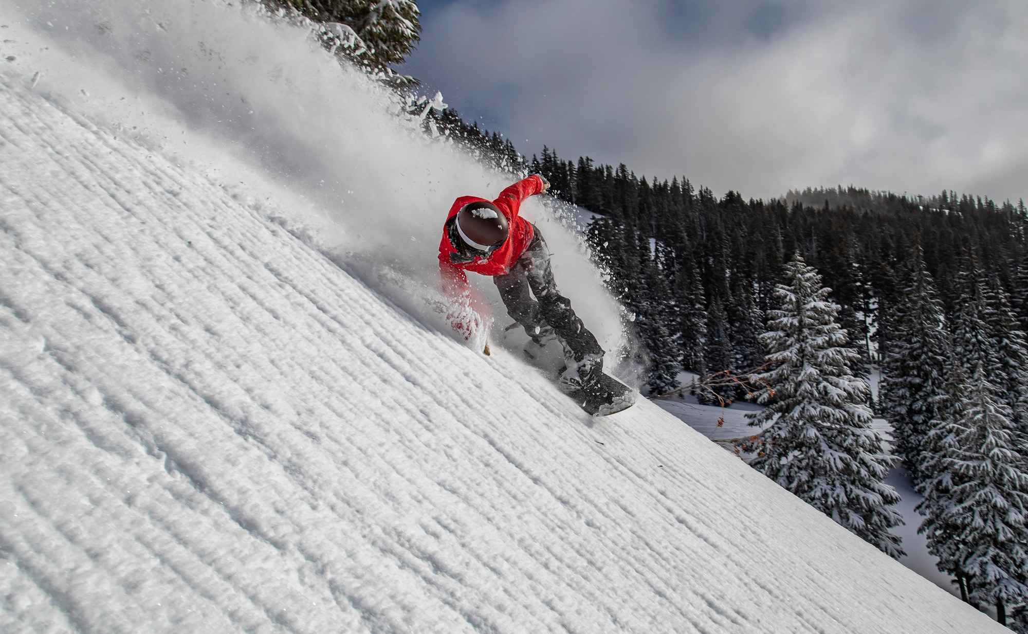 A snowboarder in a red coat shredding at Mount Hood Meadows.