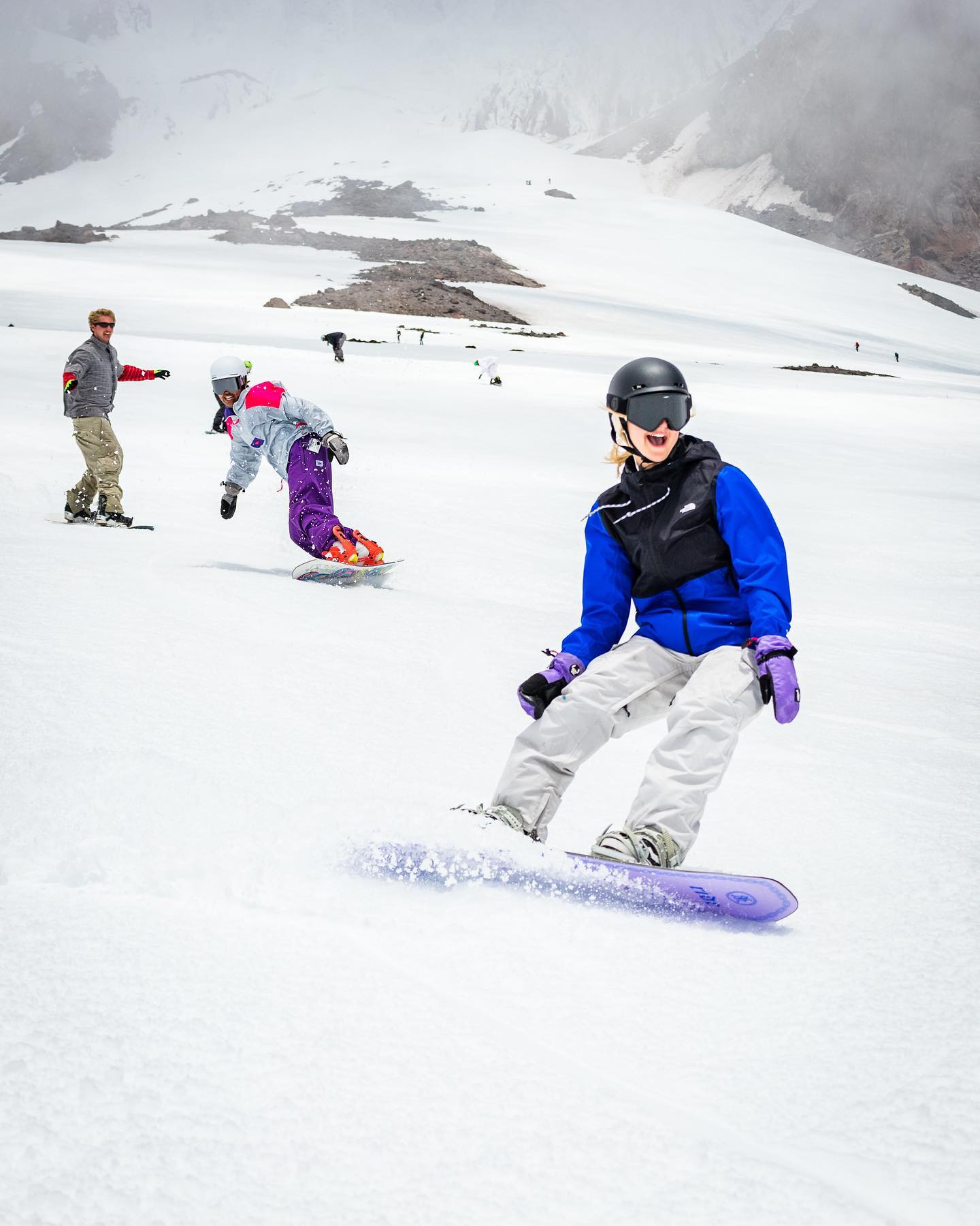 Several people smiling as they snowboard at the Timberline Lodge Ski Area.