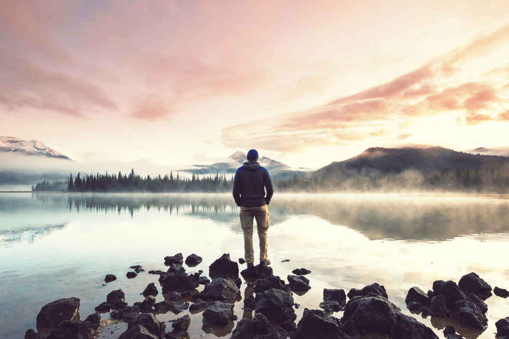 A man at sunrise standing in front of Sparks Lake near Sunriver Oregon