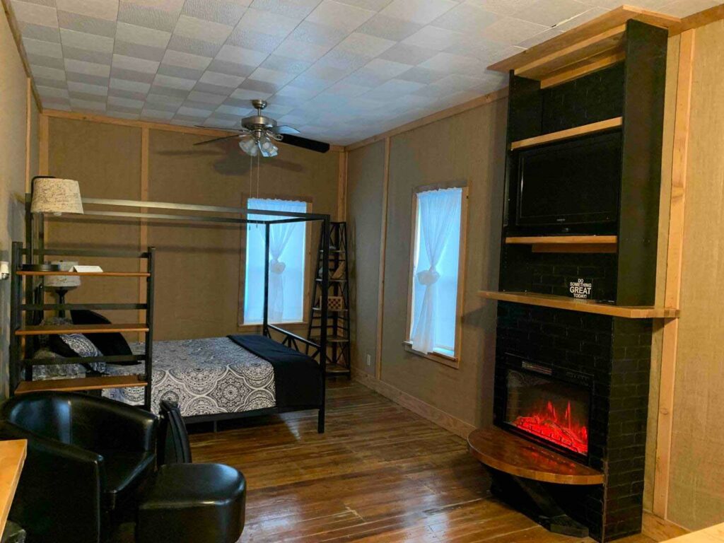The upstairs loft AirBnb. There's a bed and a fireplace with hardwood floors.