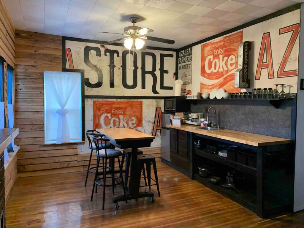 The upstairs loft AirBnb. There's a cozy chic vibe with old Coke and General store signs on the walls, hip black chairs and cabinets.