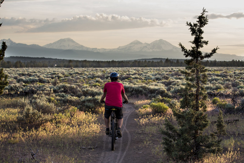 A person biking near Redmond Oregon with snowcapped mountains in the background.