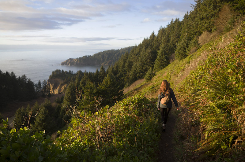 A woman hiking the gorgeous trail above the coast at sunset.