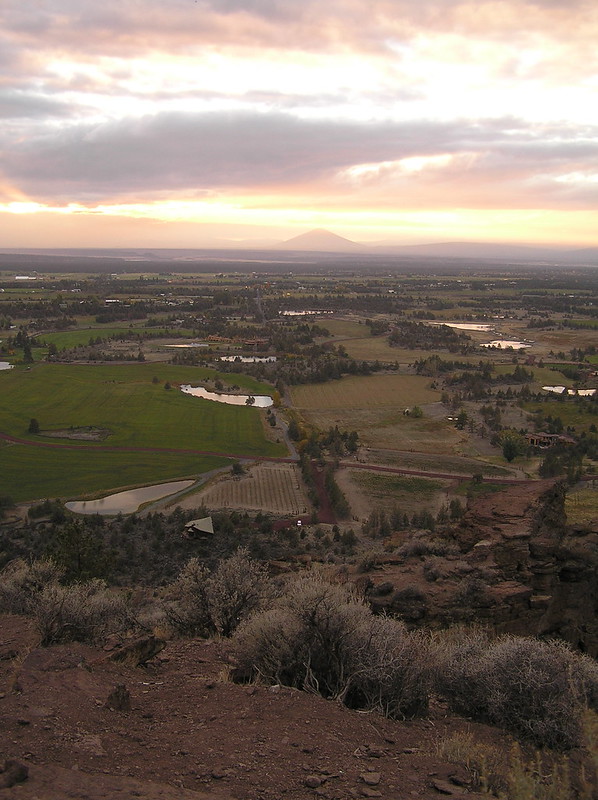 A view from up high of fields, rocky terrain, and a mountain in the distance in central Oregon.