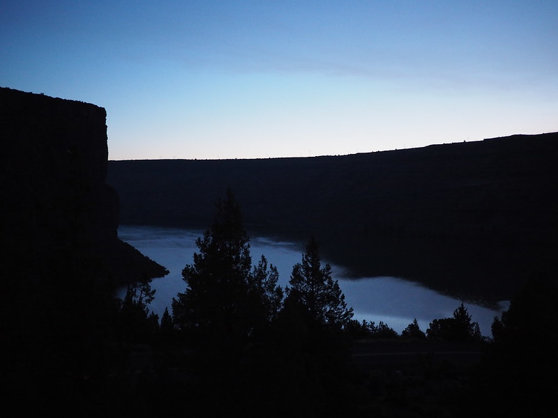 The lake at the bottom of huge cliffs just before dawn. The cliffs are dark silhouettes in this lighting.