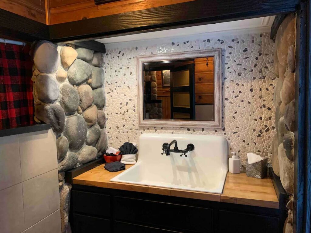 The bathroom has a unique sink and stone walls.