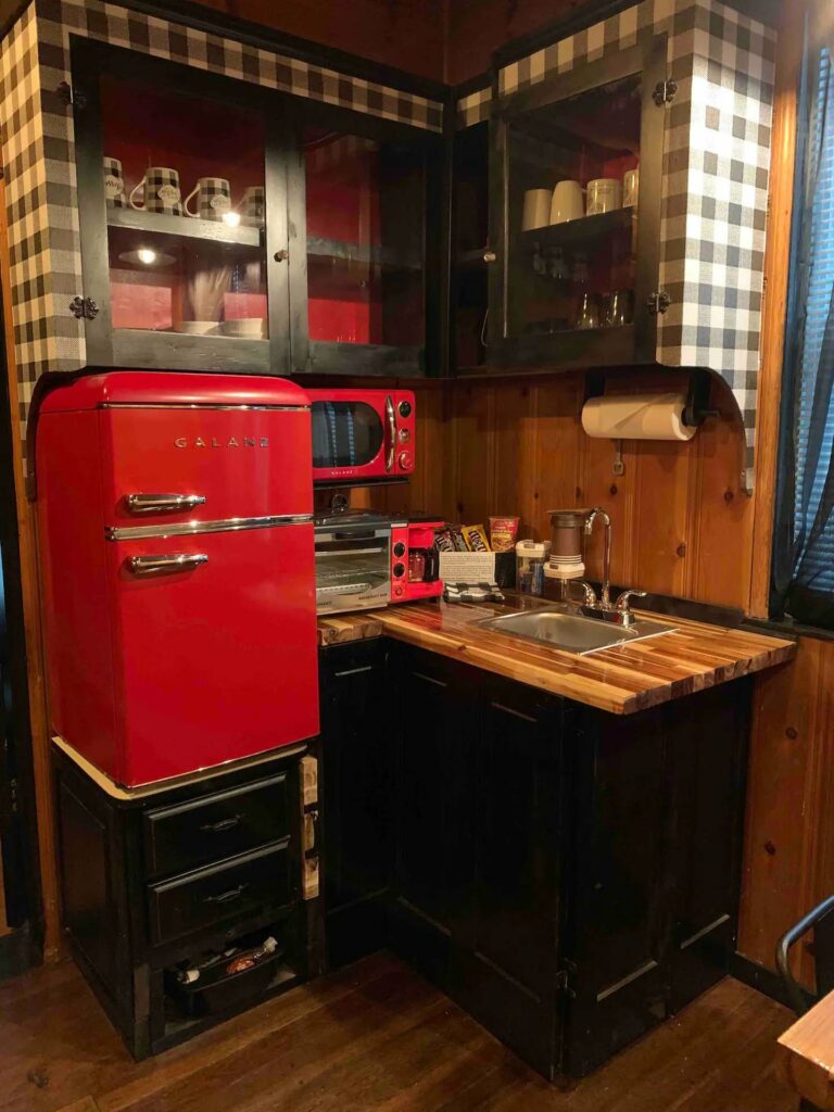 There's an old style red fridge, a small counter space and sink in the kitchen.