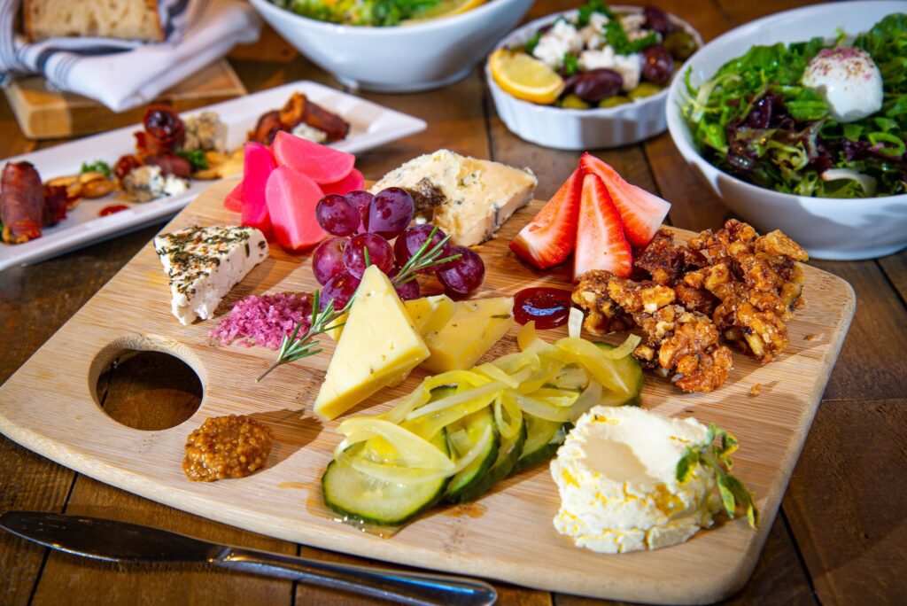 A colorful charcuterie board with a variety of foods. It looks delicious.