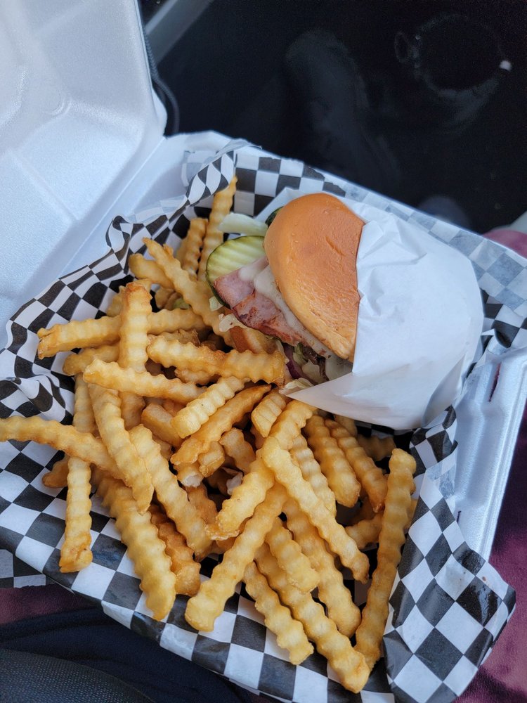 A burger and basket of fries with black and white checkered paper.