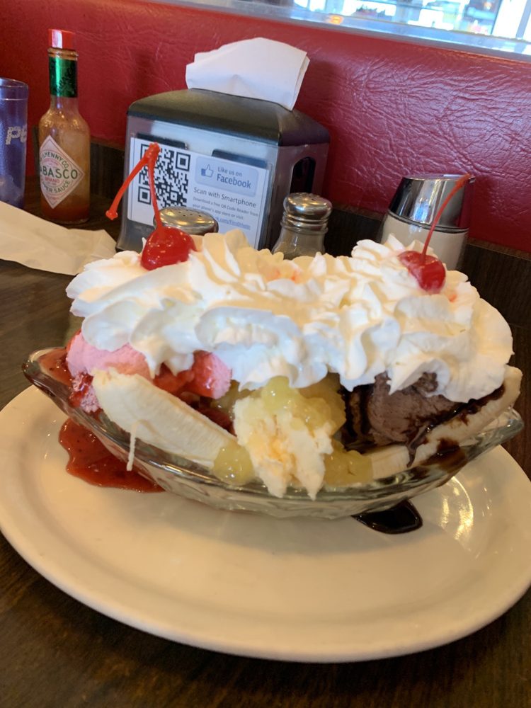 A huge bananna split topped with whip cream and cherries.