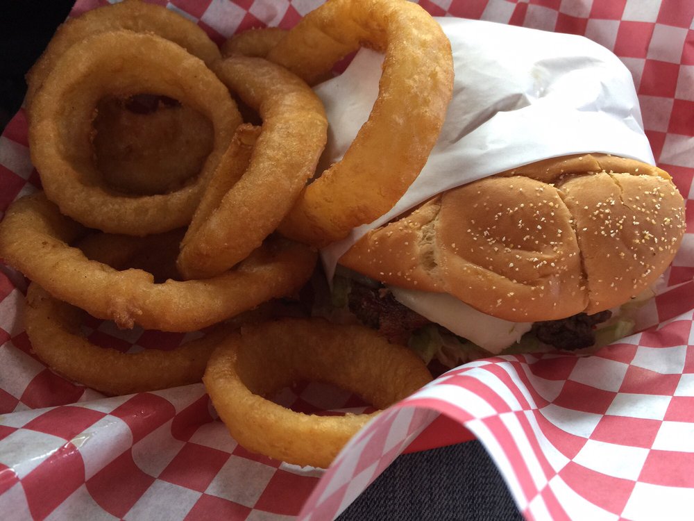A burger and onion rings on red and white checkered paper.
