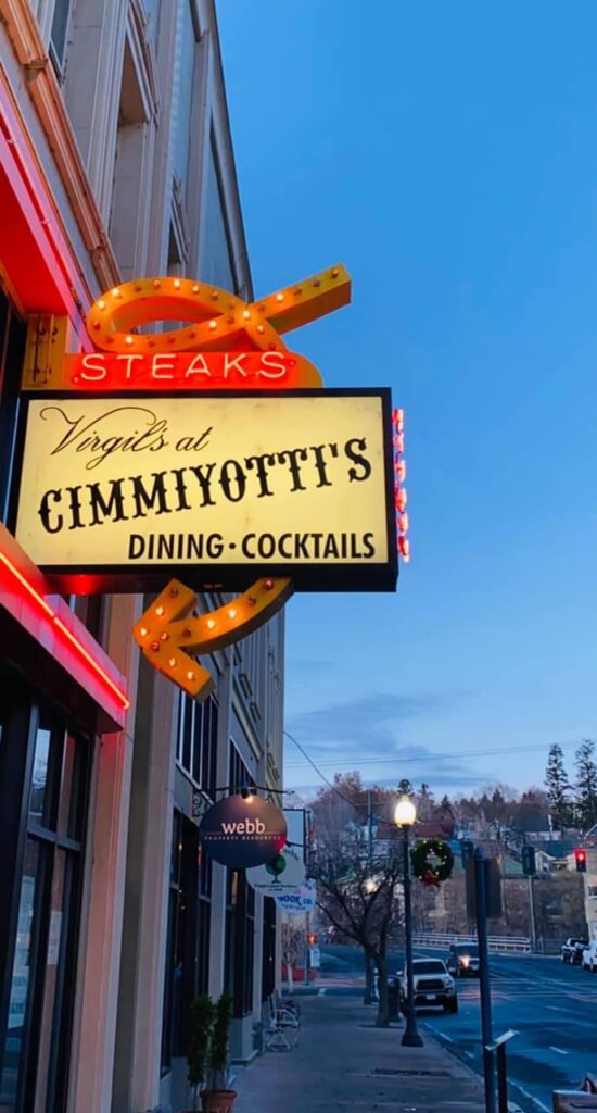 The At Cimmityotti's sign lit up at night.