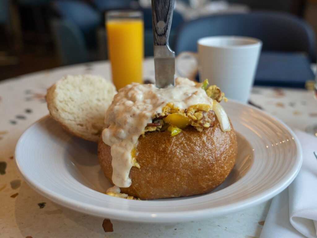 A bread bowl stuffed with scrambled eggs, bacon, sausage, country fried potatoes, onion and peppers. Served with country gravy and Tillamook cheddar.