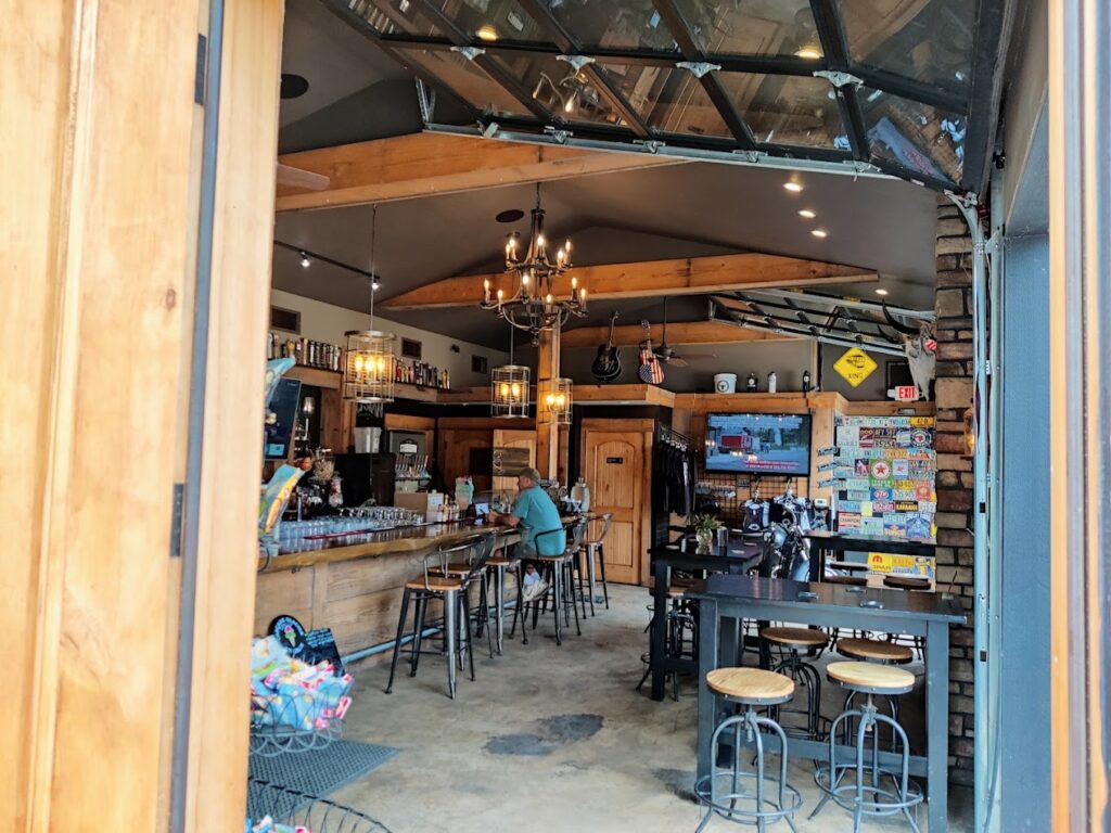 The interior of the taproom. It has a rollup glass door and wood beams.